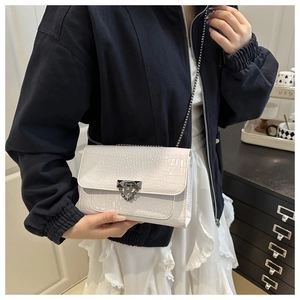 Detail of white crocodile texture leather bag with silver metal buckle and chain strap