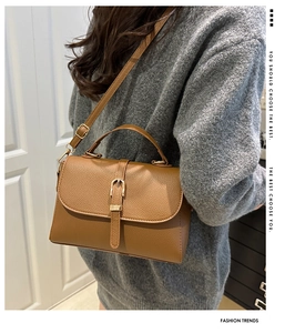 Brown lychee leather shoulder bag detail with gold buckle and adjustable strap on model