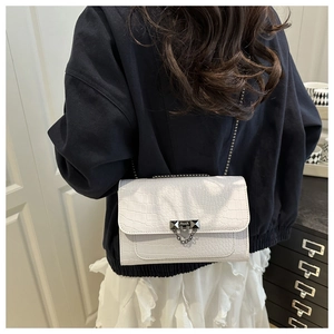 Detail view of white crocodile pattern shoulder bag with metallic lock and chain