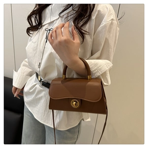 Detail der braunen Vintage Handtasche mit goldenem Drehverschluss und dünnem Gurt