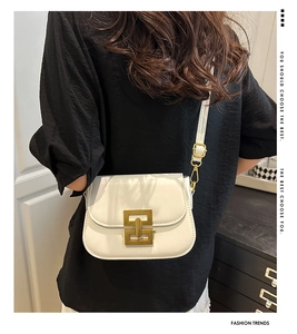 Detailed view of a white leather crossbody bag featuring a vintage gold square metal lock