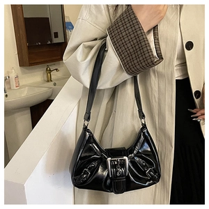 Close-up of black glossy pleated underarm bag with silver buckles and Y2K punk details