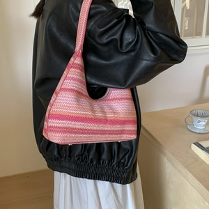 Detail of pink gradient woven hobo bag with striped straw texture and metal protective feet