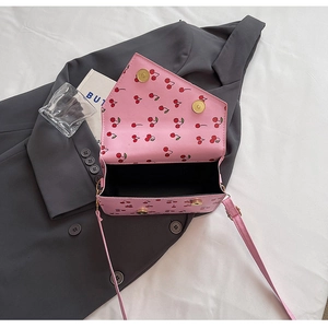 Detalle del bolso rosa con estampado de cerezas y cierres magnéticos dorados elegantes