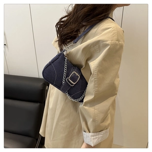 Detail of blue denim hobo bag showing silver square buckle and chunky chain strap