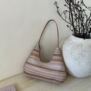 Detail of a striped knit bucket bag with zipper closure and thin shoulder strap