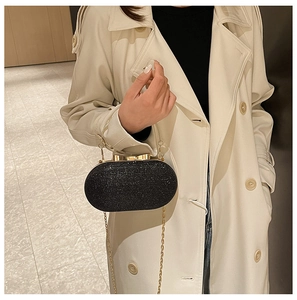 Detail of black sequined evening clutch bag with golden bow clasp and circular metal handle