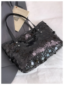 Close-up of a black sequin tote bag with a Creative Cat label and metallic textures