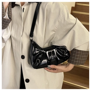Close-up of black glossy Y2K shoulder bag with silver buckle on beige trench coat