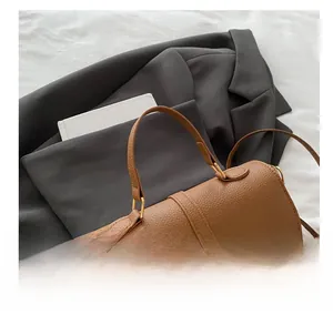 Detail view of brown lychee grain leather tote with golden buckle and top handle