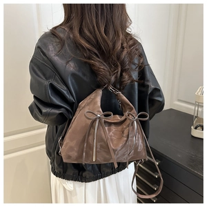 Close-up of brown suede tote bag featuring signature double bow ties and metal zipper details