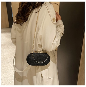 Detail of black sequined evening bag with gold chain strap on a trench coat model