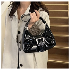 Detail of black glossy patent leather shoulder bag with metallic buckle and Y2K aesthetic