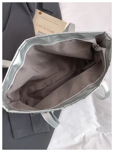 Detailed view of silver sequin tote bag interior with zipper pocket and gray fabric lining