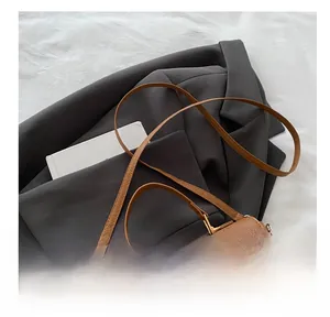 Detail of brown lychee grain leather handbag with gold buckle and adjustable strap