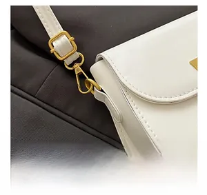 Detail of premium gold-tone metal hardware and adjustable strap on a white bag