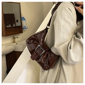 Detail of dark brown glossy patent leather shoulder bag with Y2K metal buckle accents