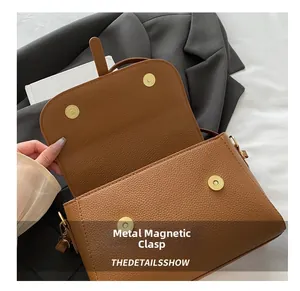 Detail of magnetic snap closures and lychee grain leather texture on a brown handbag