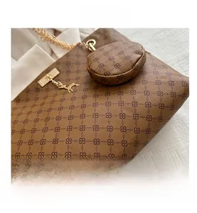 Dettaglio della borsa shopper marrone con monogramma, catena d'oro e mini pochette