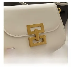 Close-up of golden geometric chain lock on white leather luxury shoulder bag