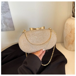 Detail of champagne gold evening clutch with sequin finish and gold bow-knot clasp