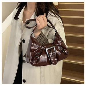 Close-up of glossy dark brown patent leather underarm bag with silver buckle details
