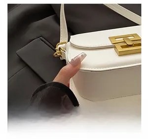 Close-up of white leather handbag featuring gold geometric buckle and precision stitching