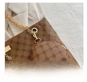 Dettaglio della borsa tote marrone vintage con monogramma e ciondolo a cervo d'oro