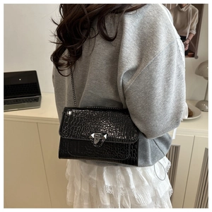 Close-up of black crocodile embossed handbag with silver metal chain and lock detail