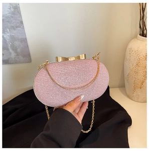Detail of pink glitter evening bag with golden bow clasp and metal chain strap