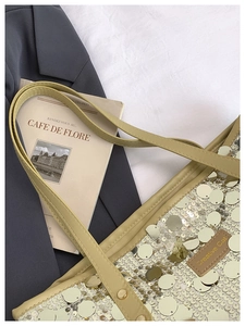 Close-up of golden sequins and beige leather strap on a high-capacity tote bag
