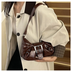 Detail of vintage Y2K dark brown shoulder bag featuring large silver metal buckle and glossy PU texture