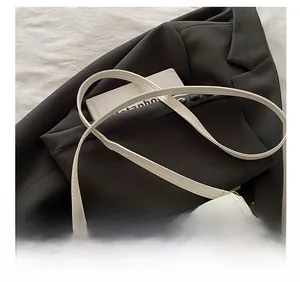 Close-up of adjustable shoulder strap design on a white retro crossbody bag with gold hardware