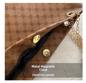Dettaglio della chiusura magnetica dorata e della catena sulla borsa tote marrone