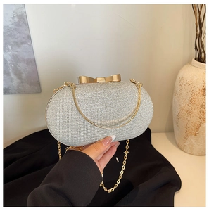 Detail of silver sequin evening bag with gold bow clasp and metallic chain strap