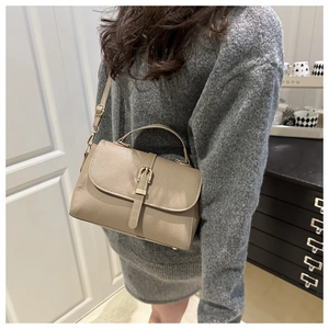 Detail of khaki lychee grain leather handbag featuring vintage metal buckle and top handle