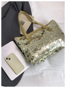 Detail shot of a large sequin tote bag with gold metallic finish and faux leather trim