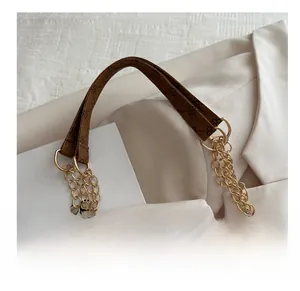 Dettaglio della tracolla monogramma marrone con catena dorata su borsa shopper
