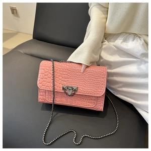 Close-up of pink croc-embossed leather texture and dark gunmetal chain detail on shoulder bag