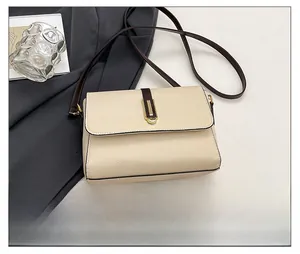 Close-up of contrast crossbody bag featuring beige pebble leather and gold metal buckle
