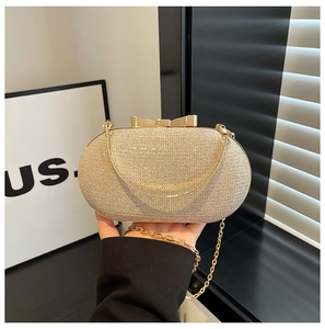 Detail of champagne gold glitter evening bag featuring a gold bow clasp and chain strap