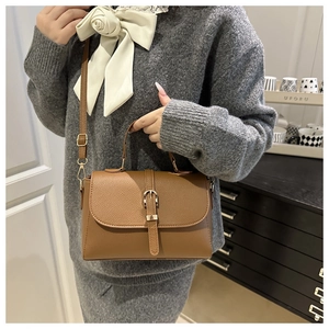 Detailed texture of brown litchi pattern leather bag with gold buckle and handle