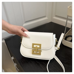 Detail of white square bag featuring a distinctive gold geometric metal lock and leather strap