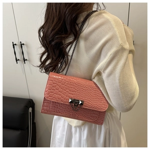Detail of coral pink crocodile texture crossbody bag with dark metal chain and rivet
