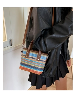 Detail der bunten geflochtenen Strohtasche mit braunem Ledergriff und silbernen Nieten