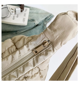Close-up of matte zipper closure and quilted puffer fabric on beige tote bag