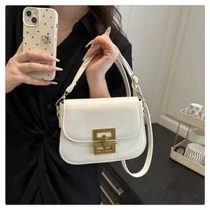 Close-up of white leather handbag featuring a vintage gold geometric metal lock and strap