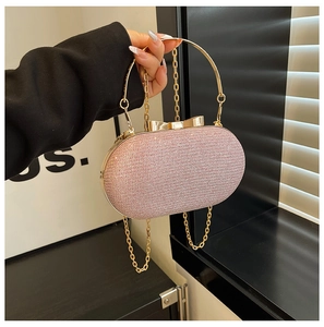 Detail of pink glitter clutch bag with golden ring handle and bow clasp in hand