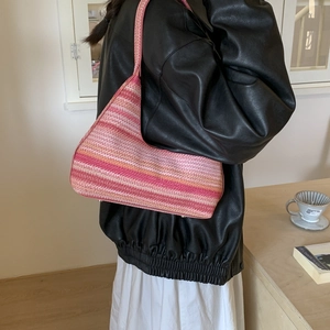Pink striped woven bucket bag for summer shoulder wear shown in a lifestyle setting