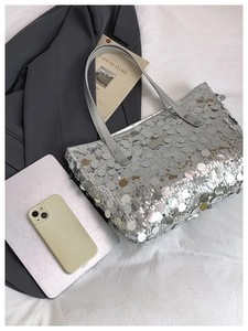 Detail of silver sequin tote bag with metallic texture and long leather handles
